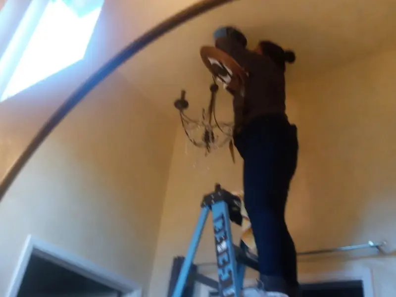 Electrician installing a chandelier in a Lewiston residence